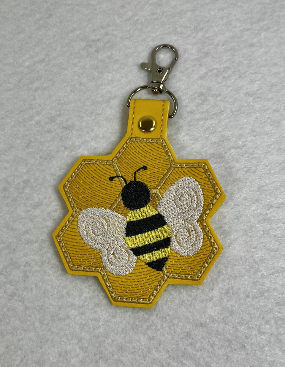 Embroidered yellow honeycomb keychain with a bee