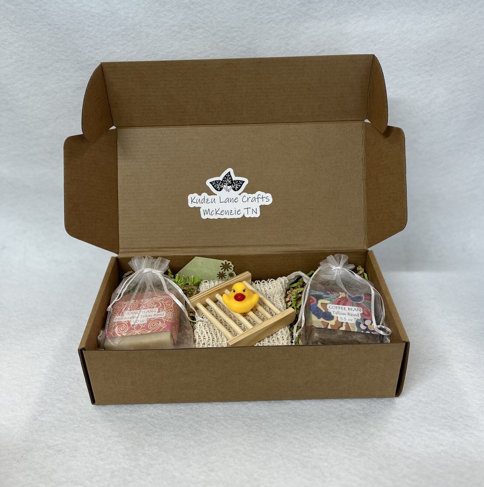 Open gift box with two bars in organza bags, a wooden drying rack and a rubber duck